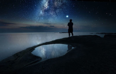 Rear view of silhouette man standing against star field at night