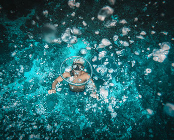 High angle view of man free diving making water rings swimming in sea