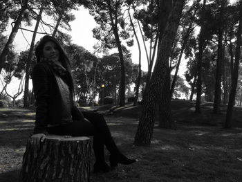 Portrait of young woman sitting on tree