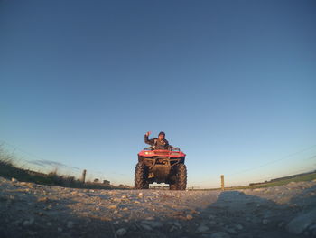 People on road by land against clear blue sky