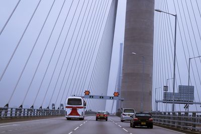 Cars on bridge against sky in city