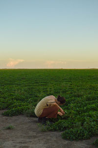 Rear view of man on field against sky during sunset