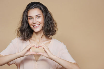 Portrait of young woman against pink background