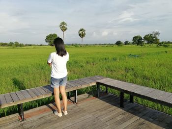 Rear view of woman standing on field against sky