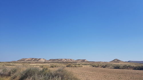Scenic view of arid landscape against clear blue sky