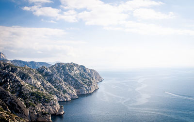 High angle view of rocky coastline against clouds