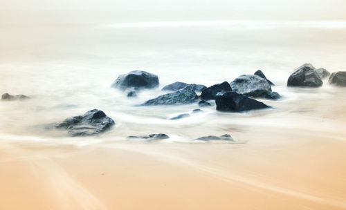 Scenic view of rocks on beach against sky