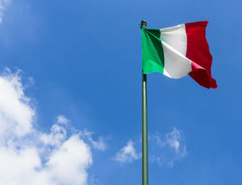 Low angle view of flag waving against blue sky