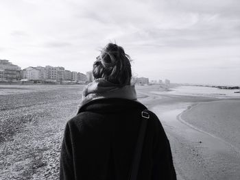 Rear view of woman standing on shore against sky