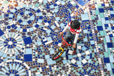 High angle view of boy cycling on mosaic walkway