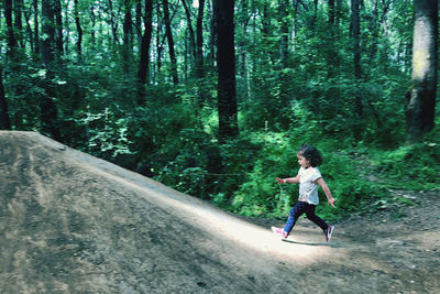 Full length of girl running on road in forest