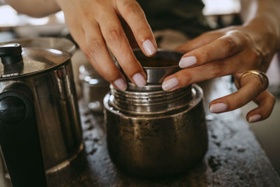 Hands of female entrepreneur preparing coffee in studio