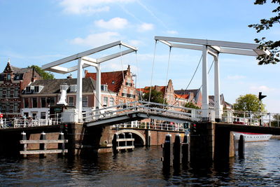 Bridge over river in city against blue sky