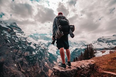 Rear view of people on snowcapped mountain against sky