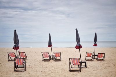 Chairs on beach against sky