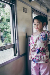 Full length of cute girl standing against window