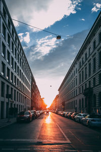 Cars on road amidst buildings in city against sky