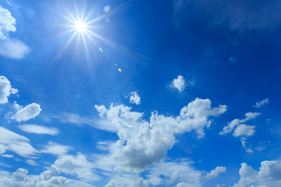 Low angle view of sunlight streaming through clouds