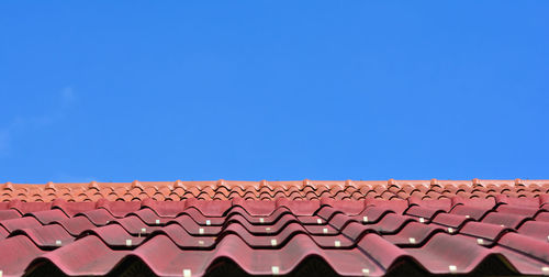 Low angle view of roof tiles against blue sky