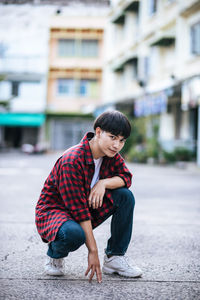 Full length of man sitting on street in city