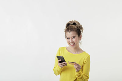 Portrait of smiling man holding smart phone against white background