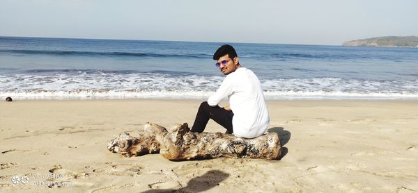 Full length of young man on beach against sky