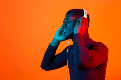 Midsection of man standing against orange wall