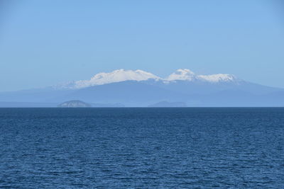 Scenic view of sea and snowcapped mountains against sky