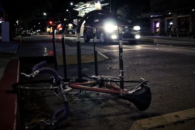 Bicycle on sidewalk by road in city at night