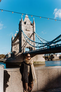 Rear view of woman standing on bridge against sky