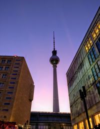 Low angle view of communications tower in city at night