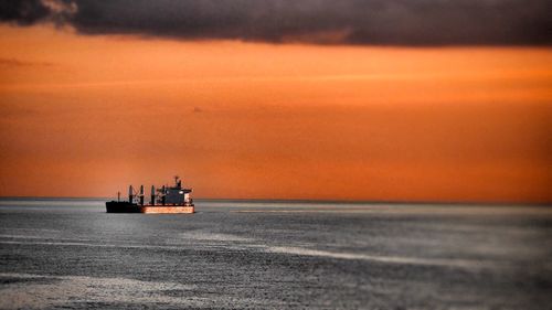 Ship on sea against orange sky during sunset