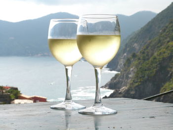 Close-up of wineglasses on table against mountains