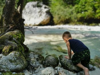 Rear view of boy on rock at beach