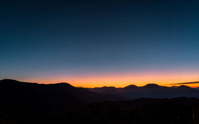 Scenic view of silhouette mountains against clear sky during sunset