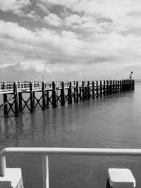 Pier on sea against cloudy sky