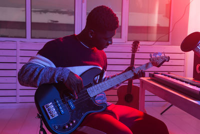 Man playing guitar against wall