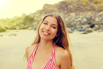 Portrait of smiling young woman standing at beach