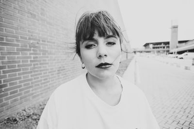 Portrait of young woman standing against wall