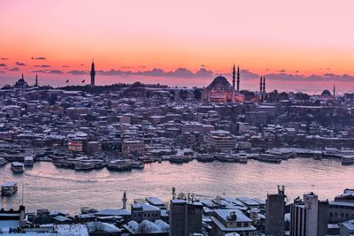 Scenic view of snow covered residential district against sky during sunset