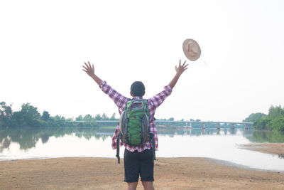 Rear view of man standing at beach against sky