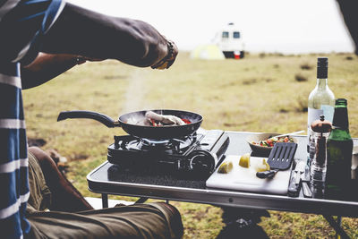 Cropped image of man preparing food on camping stove at campsite