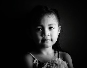 Close-up portrait of cute baby against black background