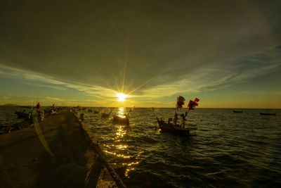 Silhouette people on sea against sky during sunset