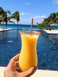 Close-up of hand holding drink in swimming pool