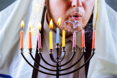 Close-up of priest blowing lit candles