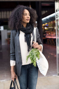 Woman looking away while standing at supermarket entrance