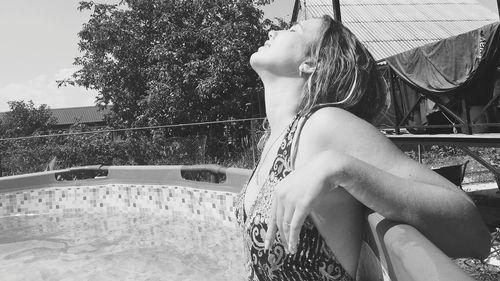 Side view of woman sitting on swimming pool