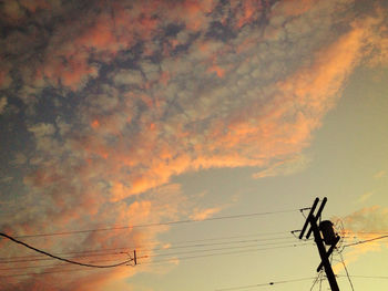 Low angle view of power lines against cloudy sky