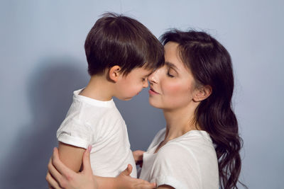 Mom and son in white t-shirts in the studio on a blue background